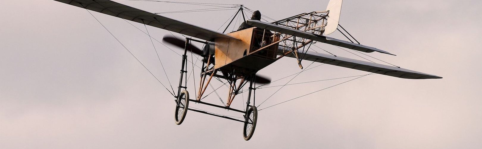 Aéroplane ancien à structure apparente volant dans un ciel pastel