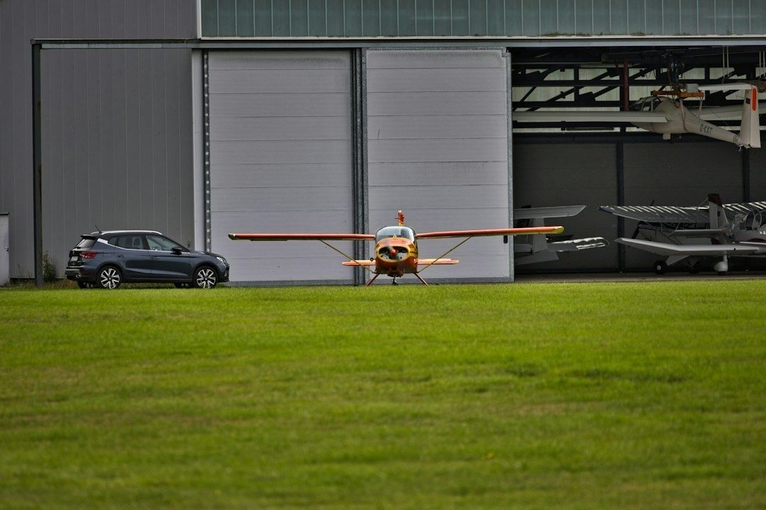 Petit avion ancien devant un hangar d